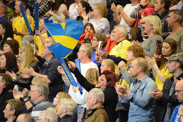 Massa människor står i publiken. En av dem viftar med en stor svensk flagga.