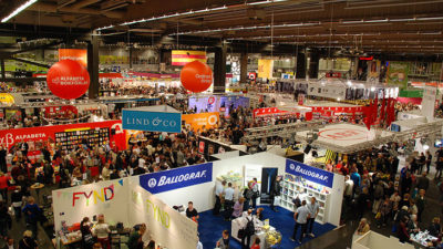 En vy av Bokmässan uppifrån. Det syns många montrar där olika företag och förlag ställer ut sina böcker. Det är väldigt mycket folk i lokalen.