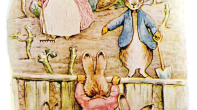 Tre kaniner i kläder står i ett trädgårdsland