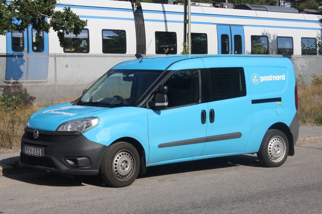 En ljusblå Postnord bil
