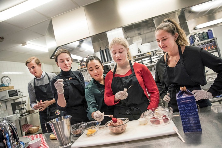 Fem elever står i ett skolkök och smakar på olika glassar.