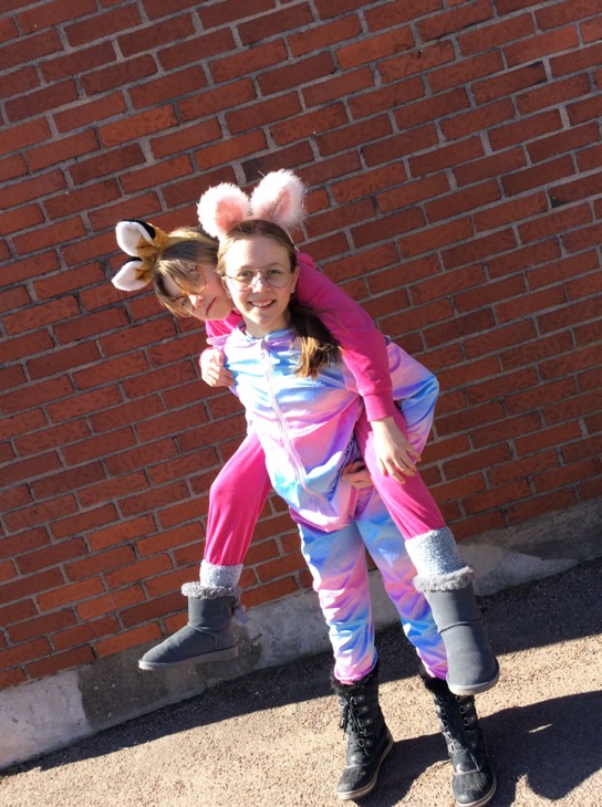 Ett barn på ryggen på ett annat barn. Barnen har kaninöron på sig och färgglada kläder.