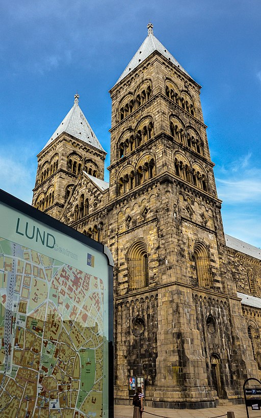 Lunds domkyrka bakom en stadskarta över staden. Himlen är klarblå.