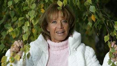 Lill-Babs står under björkgrenar som hänger ner över henne. Hon håller isär grenarna med händerna. Hon har en fluffig täckjacka och en rosa stickad tröja med polokrage. Håret är halvlångt, brunt och blont med lugg. Hon har rosa läppstift och tittar in i kameran.