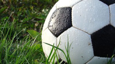 Närbild på en fotboll i gräset.