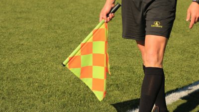 En fotbollsdomare meden flagga.