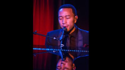 John Legend sitter och sjunger bakom ett piano