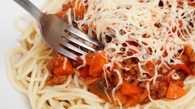 Närbild på pasta med tomatsås och en gaffel.