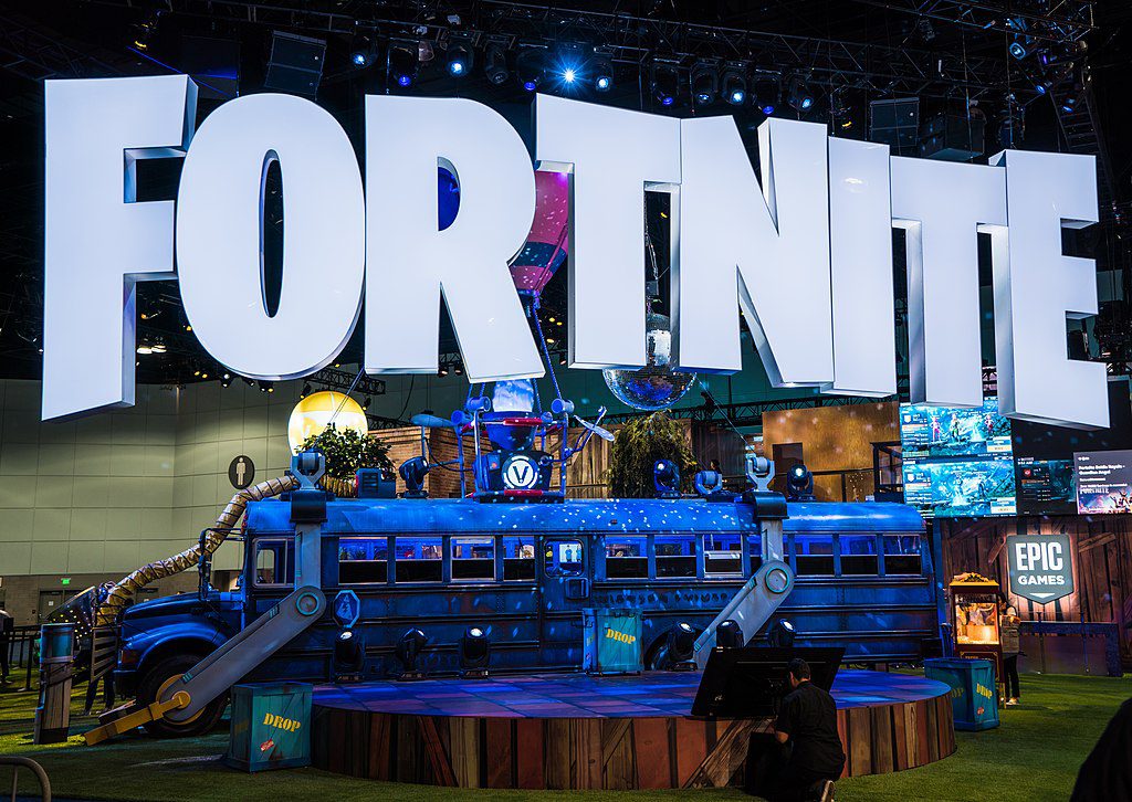 Stora bokstäver som bildar ordet Fortnite hänger ovanför en gammal buss.