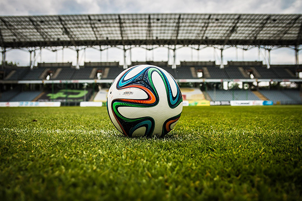 Foto på en fotboll som ligger på en stor fotbollsplan.