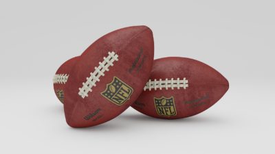 Två amerikanska fotbollar ligger bredvid varandra. De är ovala, men spetsiga.