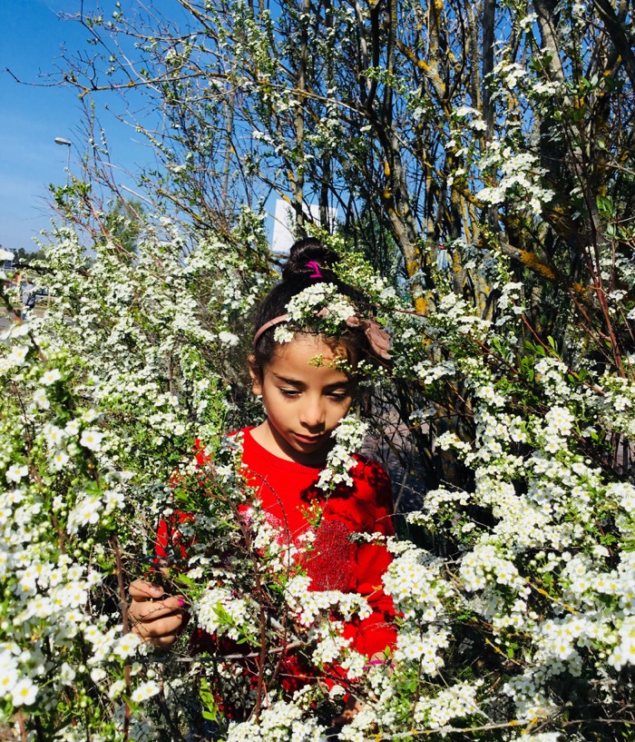 Flicka mitt i blommande buske