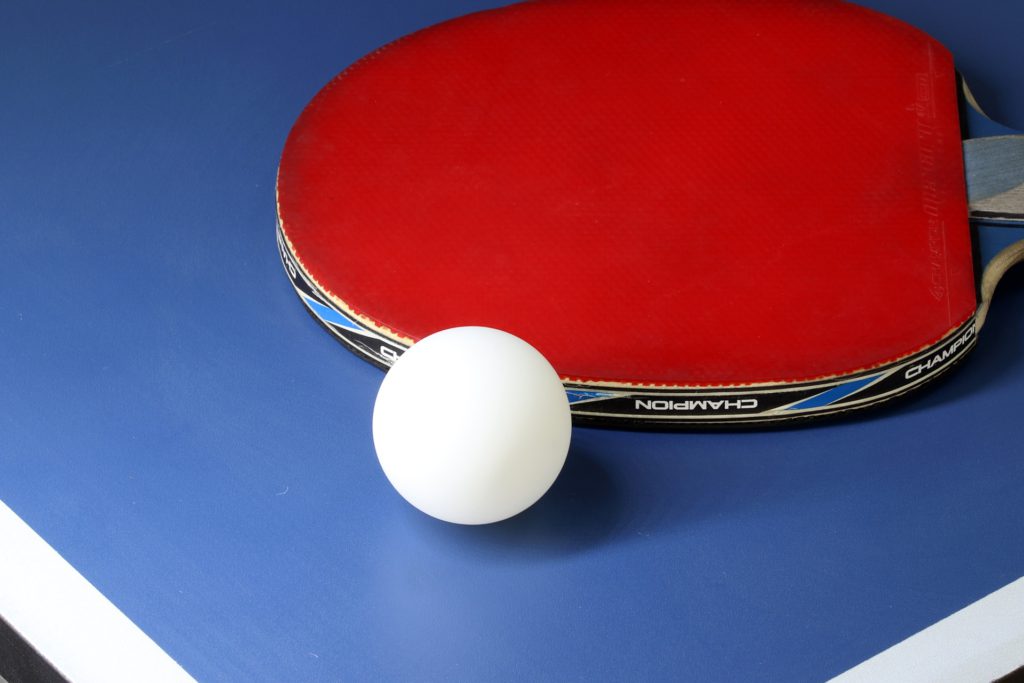 Ett bordtennisrack och en pingpongboll ligger på ett bord.
