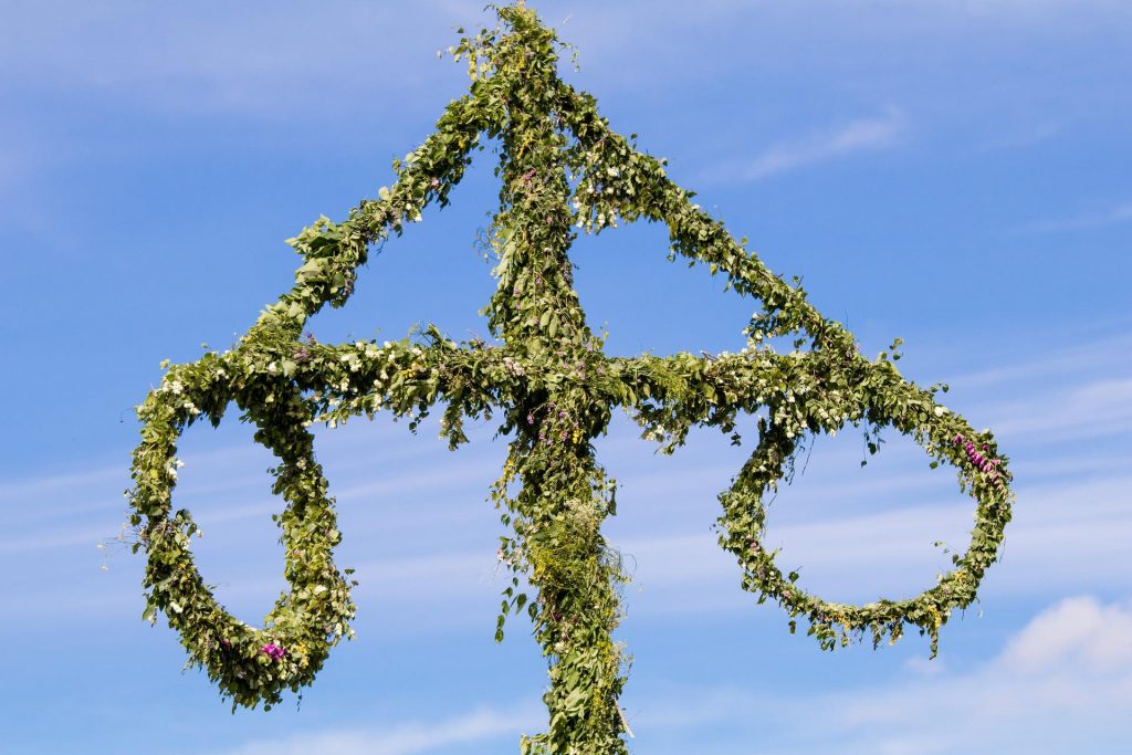 En midsommarstång mot en blå himmel.